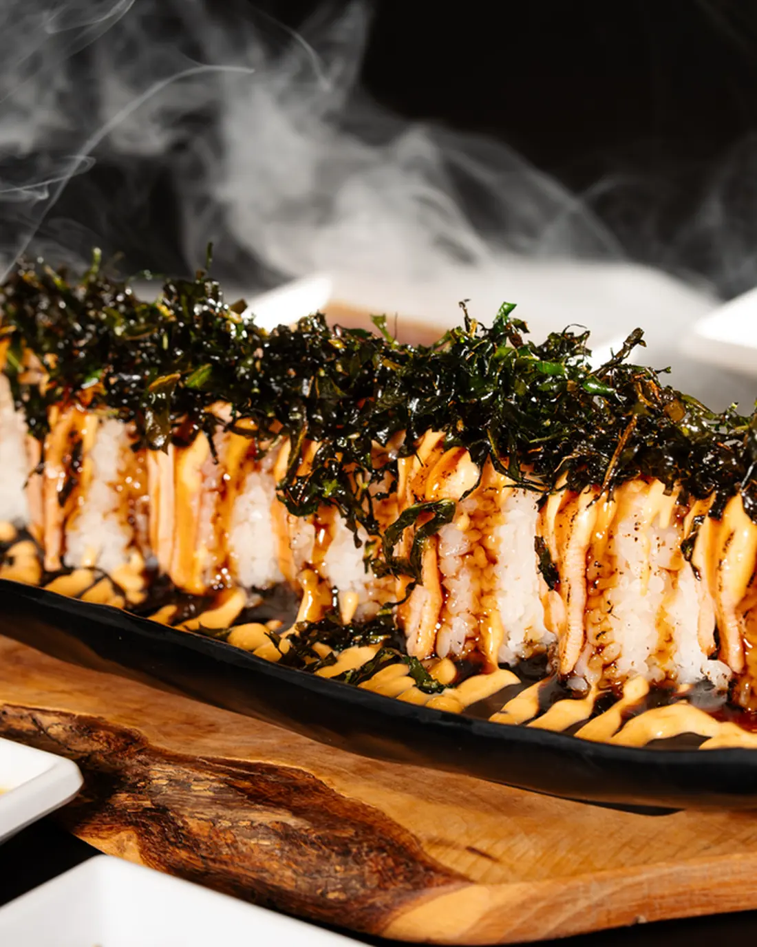 Kingdom Sushi specialty roll finished at the pass, with smoke rising from the board