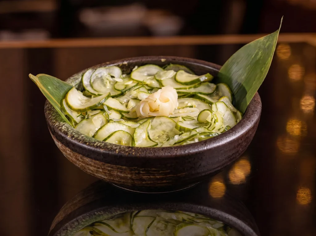Sunomo at Kingdom Sushi, thinly sliced cucumber in a light vinegar dressing topped with pickled ginger, served in a rustic stone bowl with a bamboo leaf